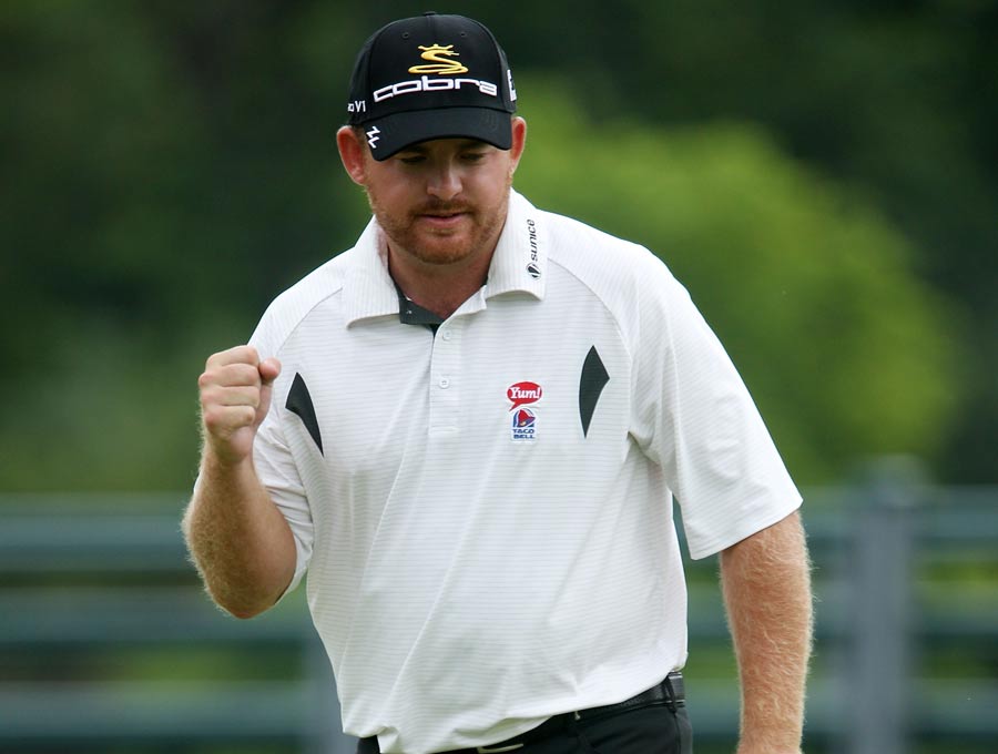 J.B. Holmes celebrates as he holes a putt for birdie on the 18th