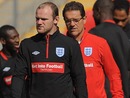 Wayne Rooney looks on with Fabio Capello