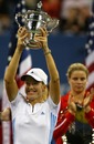 Justine Henin-Hardenne raises the trophy as Kim Clijsters looks on
