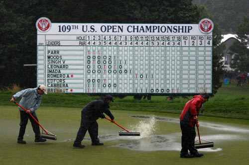 Members of the grounds staff work on a soggy 18th green at the 2009 US Open
