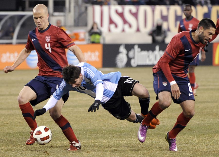 Lionel Messi is tripped up as he attempts to go between Michael Bradley and Clint Dempsey