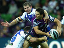 Cooper Cronk struggles to evade the clutches of two Bulldogs