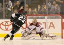 Dustin Brown of the LA Kings squeezes the ball past Louis Domingue of the Phoenix Coyotes