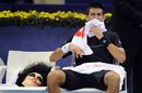 Novak Djokovic sits next to a mask