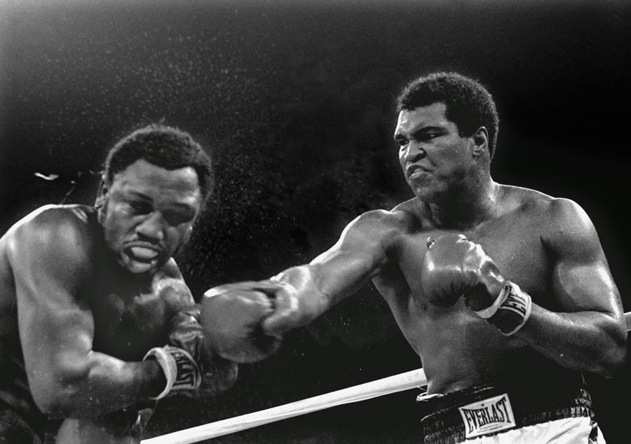 Spray flies from the head of Joe Frazier as Muhammad Ali connects 