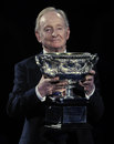 Rod Laver carries the trophy onto the court ahead of the final