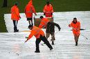 Ground staff attempt to clear water off the covers