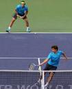 Marc Lopez meets the ball at the net with doubles partner Rafael Nadal watching on