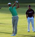 Tiger Woods hits a shot under the watchful eye of Sean Foley