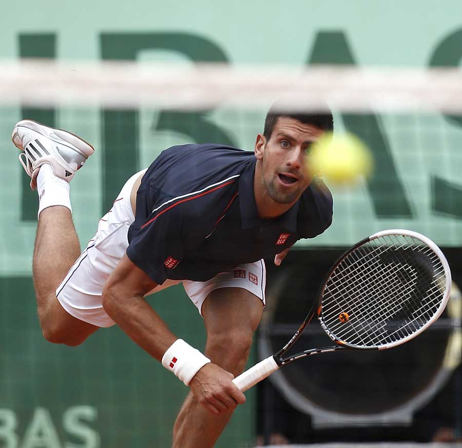 Novak Djokovic sends a serve over the net