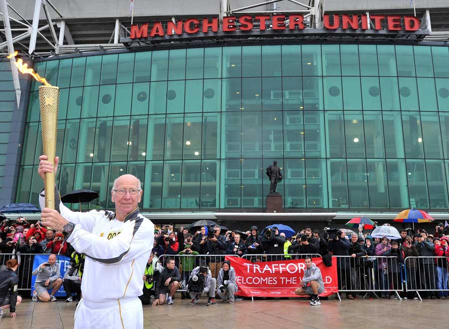 Sir Bobby Charlton holds the Olympic Flame outside Old Trafford