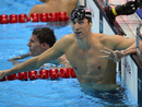 Michael Phelps gesticulates after winning gold as Ryan Lochte reflects