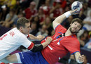 Michael Knudsen of Denmark grabs Momir Rnic of Serbia in a  handball preliminary match
