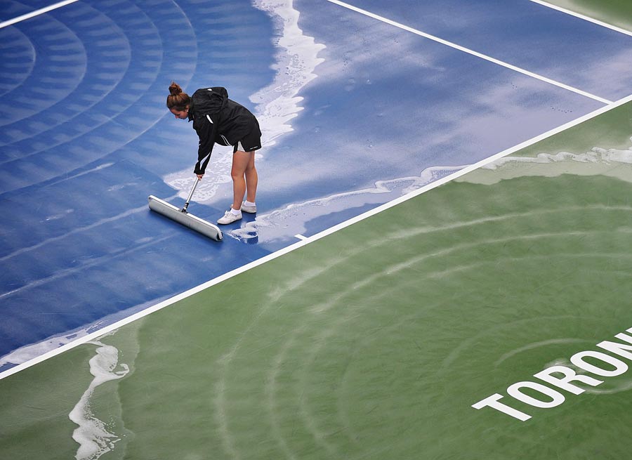 A worker dries the court during a rain delay