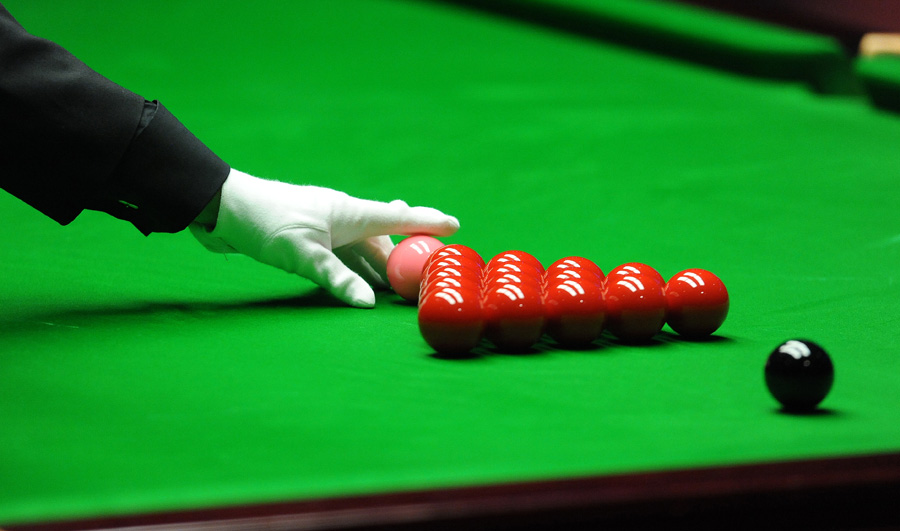 The snooker referee replaces the pink ball ahead of a new frame