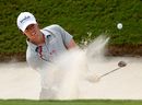 Rory McIlroy plays a bunker shot on the first hole