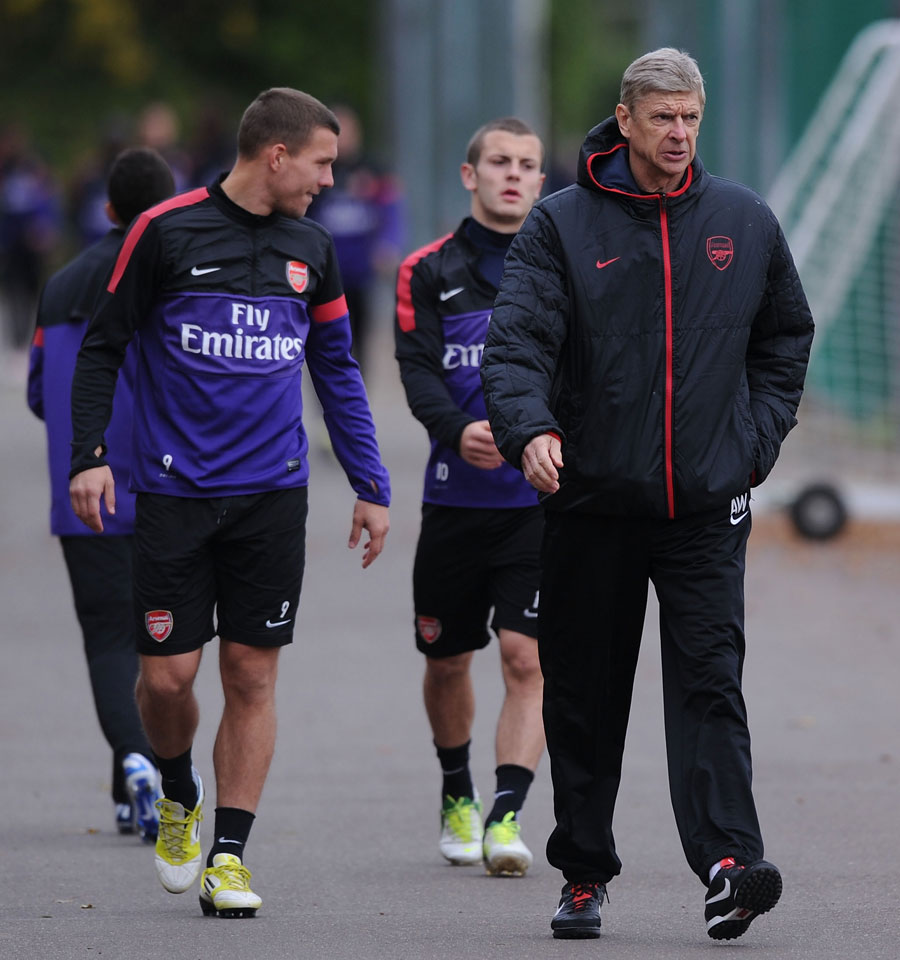 Arsene Wenger and Lukas Podolski talk before a training session