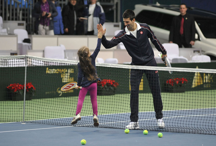 Novak Djokovic high-fives a budding tennis player