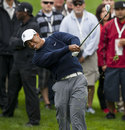 Tiger Woods hits his ball out of the rough on the sixth hole