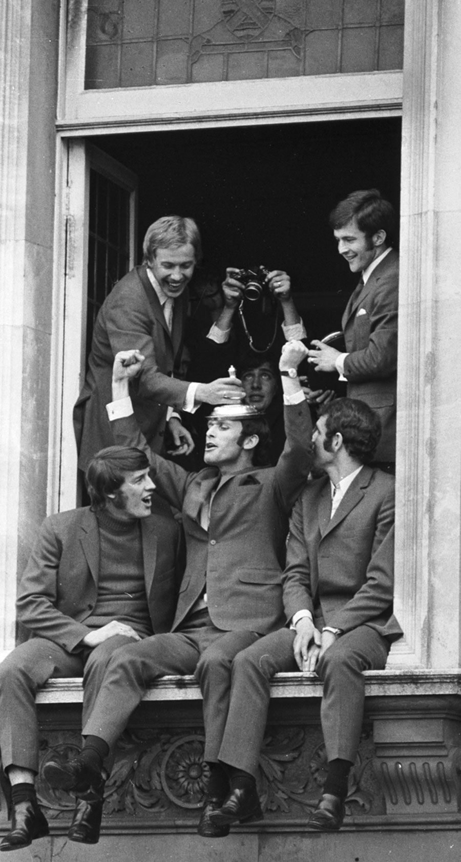 Chelsea players celebrate their FA Cup win, precariously placed on a balcony