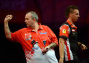 Phil Taylor takes aim as Jerry Hendriks walks past