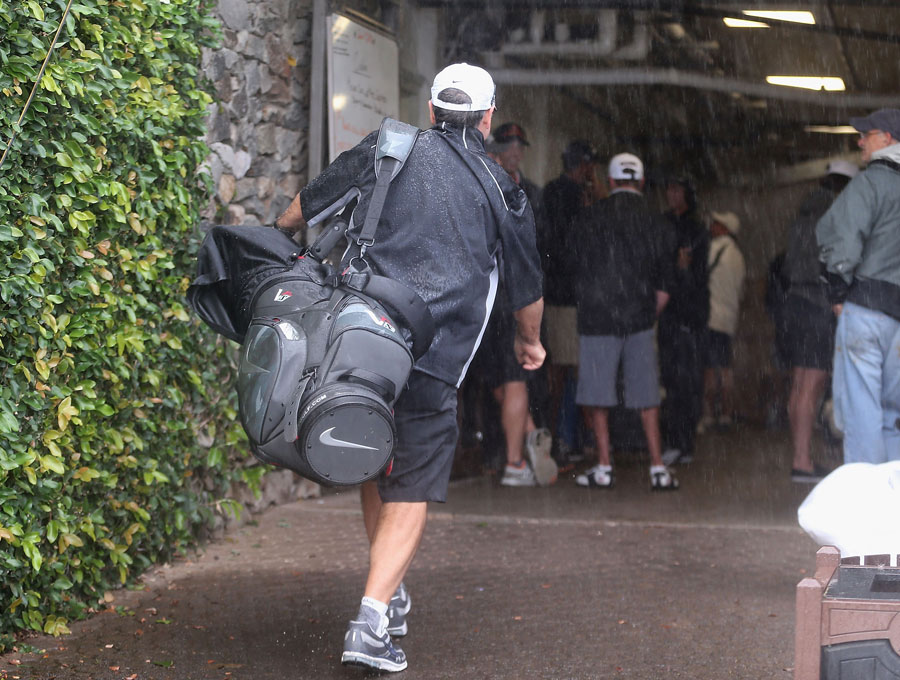 A caddie walks to shelter from the rain during a weather delay