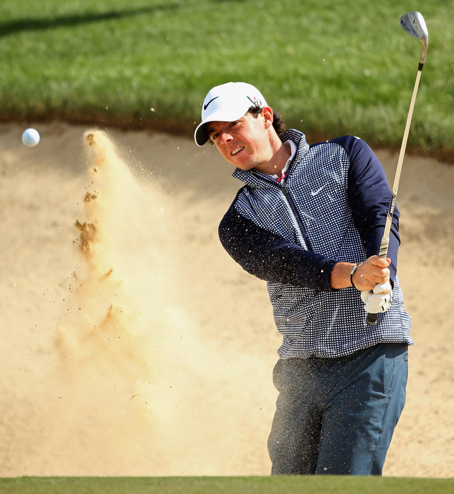 Rory McIlroy splashes out of a bunker during practice