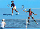 Venus Williams hits a volley as Serena Williams closes in