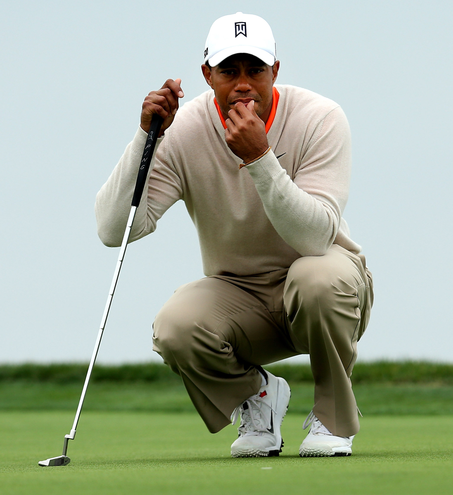Tiger Woods crouches to read the green