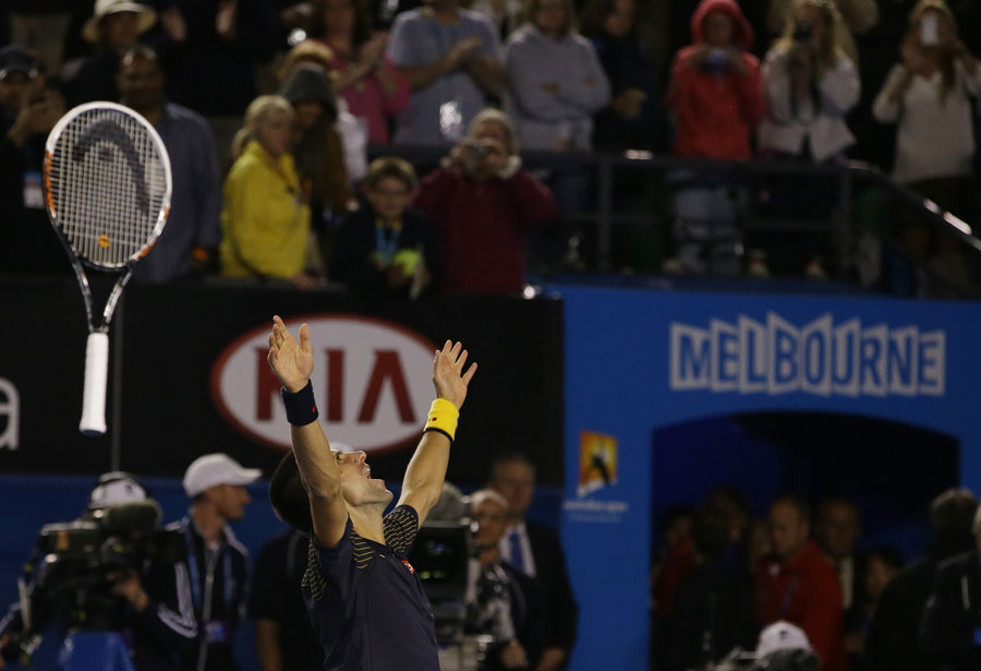Novak Djokovic throws his racket in the air after sealing victory