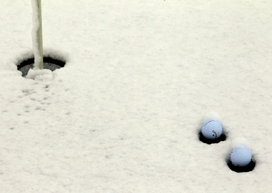 Golf balls sit on a snow-covered green