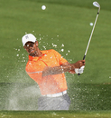 Tiger Woods chips out of a bunker during practice