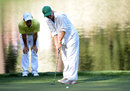 Rory McIlroy checks the line of girlfriend Caroline Wozniacki's putt during the par-3 competition at Augusta