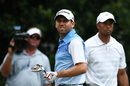 Sergio Garcia walks off the tee as Tiger Woods strides in