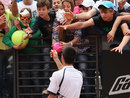 Fans try to grab a wristband thrown to them by Novak Djokovic
