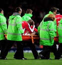 William Gallas holds his head as he is carried off the pitch on a stretcher