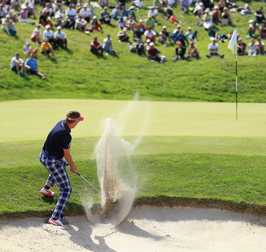 Ian Poulter splashes from a bunker