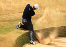 Adam Scott escapes from a bunker at the first