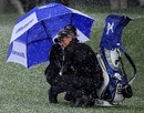 Luke Donald shelters from the hail under his umbrella