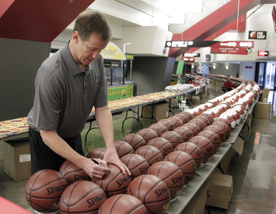 Coach Terry Stotts signs one of over 350 basketballs during the Portland Trail Blazers media day