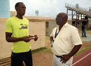 Usain Bolt and coach Glen Mills chat during a training session