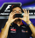 Mark Webber takes a photo on his phone during a press conference