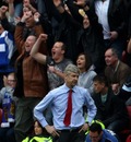 Arsene Wenger looks dejected as Wigan Athletic supporters celebrate