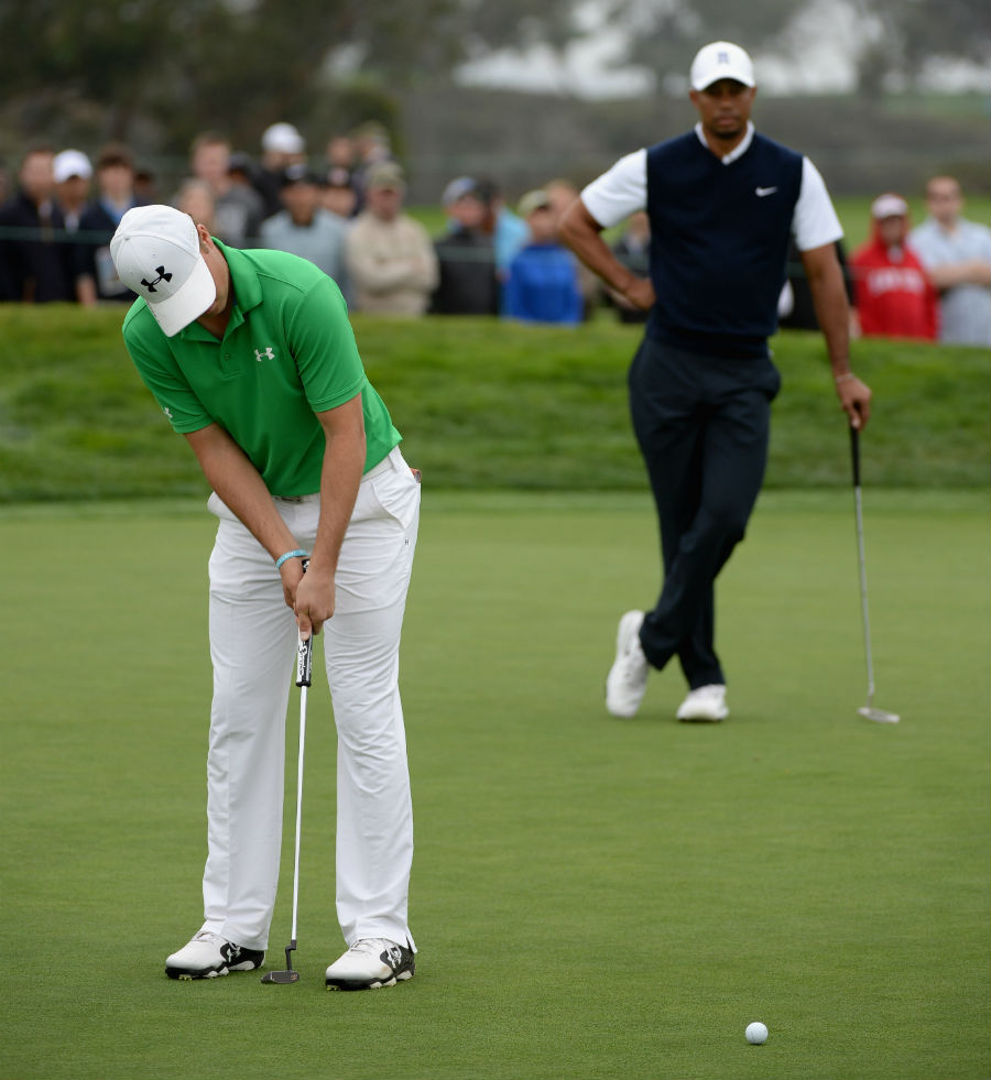 A frustrated Tiger Woods watches as Jordan Spieth makes a putt during their second round