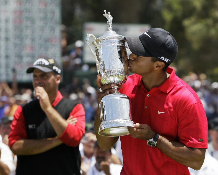 Tiger Woods kisses the trophy as Rocco Mediate looks on