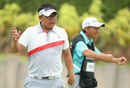 Panuphol Pittayarat and his caddie celebrate after holing a birdie putt on the 18th hole to shoot 63