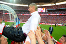 A beer-soaked Arsene Wenger is hoisted into the air by his players