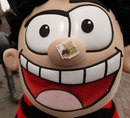 Dennis the Menace poses with a stamp featuring The Beano comic on his nose