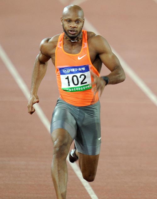 Asafa Powell runs in the men's 100m competition