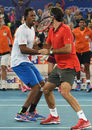 Gael Monfils and Roger Federer celebrate a point during an IPTL doubles match